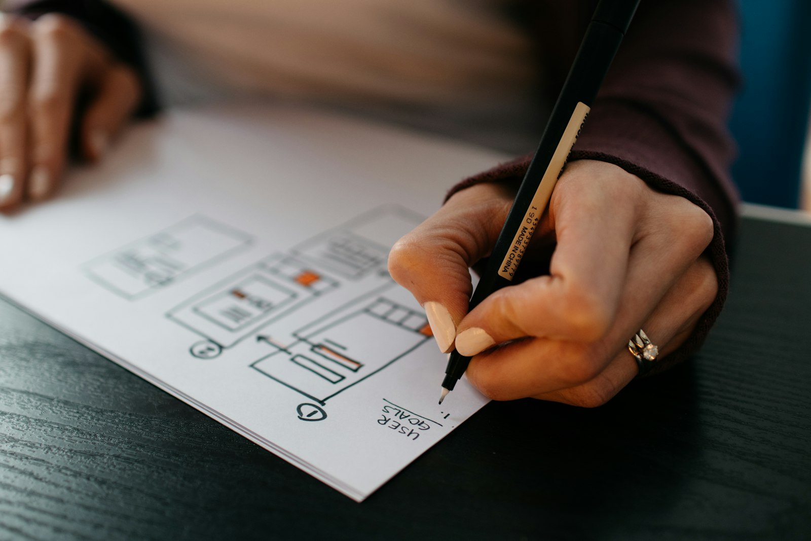 Hand sketching a website interface layout on paper